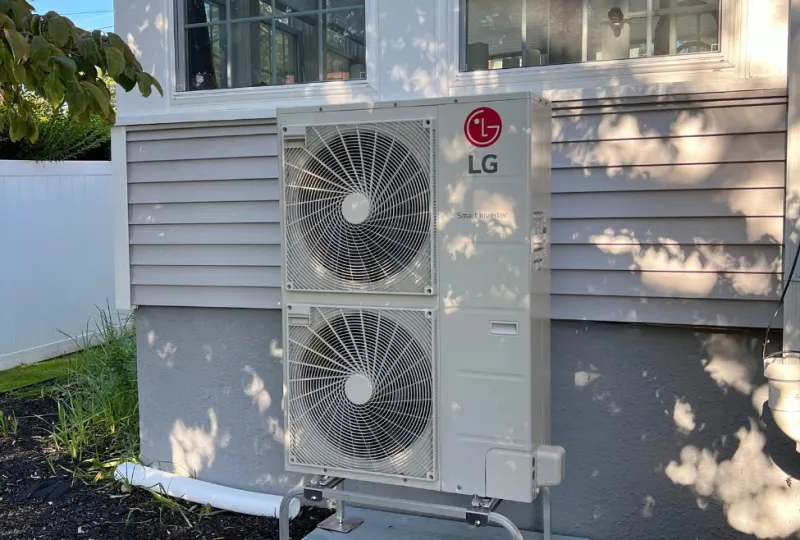 Dual-fan ductless mini split outdoor unit installed on a house